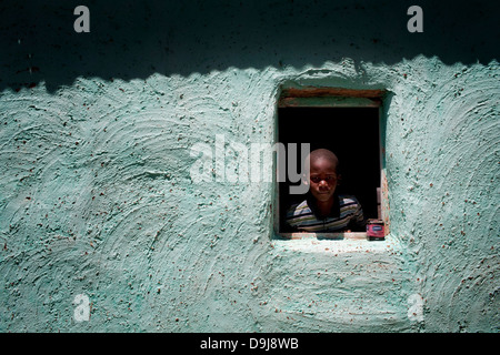 Young boy looks out of his bedroom window in rural Transkei, South Africa Stock Photo