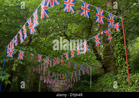 Hundreds of union jack flag bunting stretches back downhill through woods towards the local station during the annual Royal Ascot horseracing festival in Berkshire, England. Royal Ascot is one of Europe's most famous race meetings, and dates back to 1711. Queen Elizabeth and various members of the British Royal Family attend. Held every June, it's one of the main dates on the English sporting calendar and summer social season. Over 300,000 people make the annual visit to Berkshire during Royal Ascot week, making this Europe’s best-attended race meeting with over £3m prize money to be won. Stock Photo