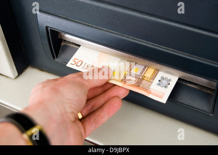 Hand takes 50 Euro Bill from bancomat slot Stock Photo