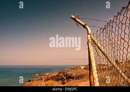 Corner post of chicken wire fence with broken strands of barbed wire above, on the coast, near Alcala, Tenerife, Canary Islands, Stock Photo