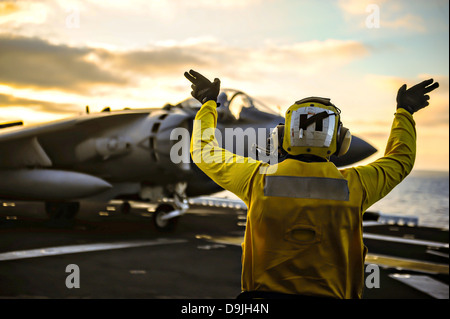 A US Navy deck crew directs a Marine Corp AV-8B Harrier fighter jet before take off on the flight deck of the amphibious assault ship USS Boxer during exercise Dawn Blitz June 12, 2013 near San Diego, CA. Stock Photo