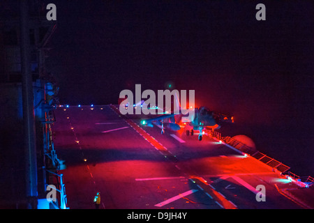 A US Marine Corp AV-8B Harrier fighter jet performs a night landing on the flight deck of the amphibious assault ship USS Boxer during exercise Dawn Blitz June 12, 2013 near San Diego, CA. Stock Photo