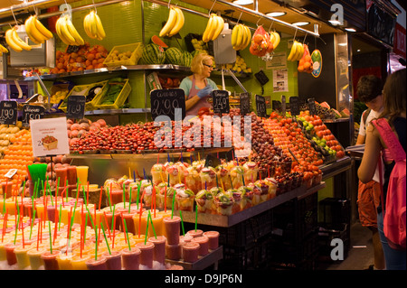 People buying fruit displayed at a market stall shop in La Boqueria  in Barcelona Spain Stock Photo