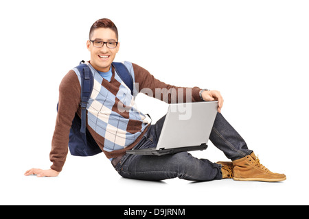 Smiling handsome guy sitting on a floor with laptop and looking at camera Stock Photo