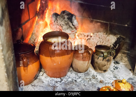 Chickpeas and other pulses in terracotta jars, cooking by an open fire. Stock Photo