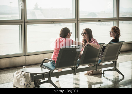 Two teenage girls and woman sitting in airport departure lounge Stock Photo