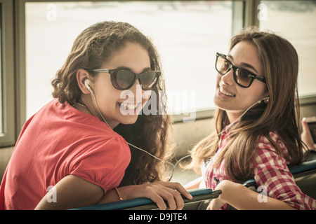 Two teenage girls wearing sunglasses listening to music Stock Photo