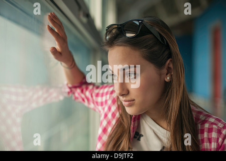 Teenage girl looking through window Stock Photo