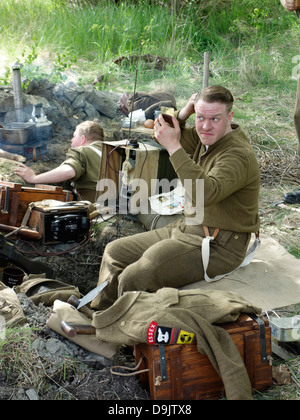 Historical re-enactment of ww2. British soldier in the trench finds time to comb his hair. Stock Photo