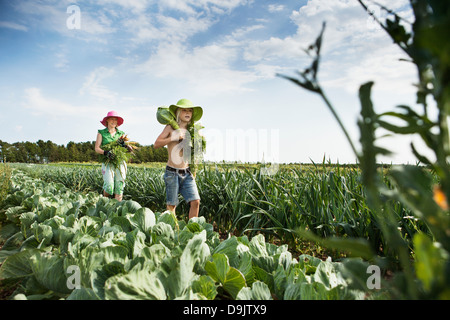 Mother and daughter carrying vegetables in field Stock Photo