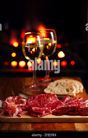 Platter of serrano jamon Cured Meat with cozy fireplace and wine background Stock Photo