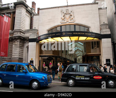Iconic black cab in front of the Burlington Arcade, a covered shopping arcade that runs behind Bond Street from Piccadilly through to Burlington Gardens showing the Royal Academy of Arts to the left, London, England, United Kingdom Stock Photo