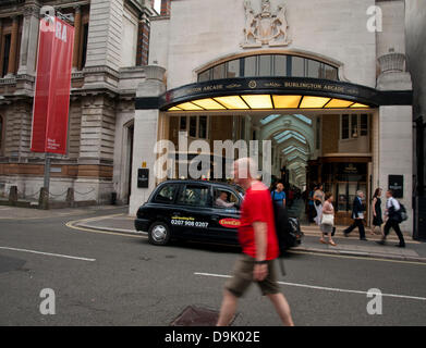 Iconic black cab in front of the Burlington Arcade, a covered shopping arcade that runs behind Bond Street from Piccadilly through to Burlington Gardens showing the Royal Academy of Arts to the left, London, England, United Kingdom Stock Photo