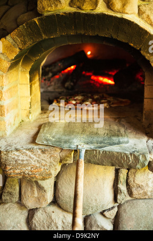 PIZZA COOKING IN WOOD FIRED OVEN Stock Photo