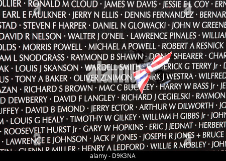 closeup of names on the traveling Vietnam war memorial wall with red white blue American America flag ribbon USA Stock Photo