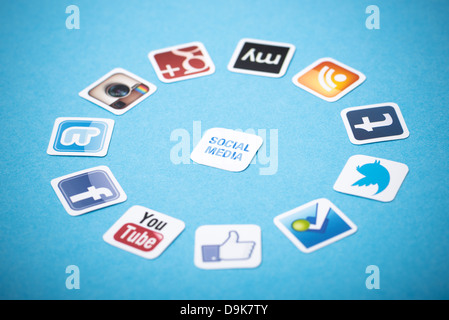 A logotype collection of well-known social media brands printed on paper and placed around on a blue background. Stock Photo