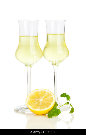 Two glasses of italian Limoncello liqueur, lemon half and lemon balm leaves isolated on white background Stock Photo