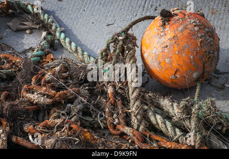 A tangled fishing net with a orange fishing buoy on top Stock Photo - Alamy