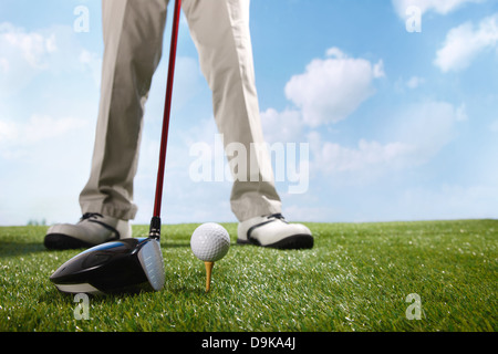 Golf player teeing up to hit ball Stock Photo