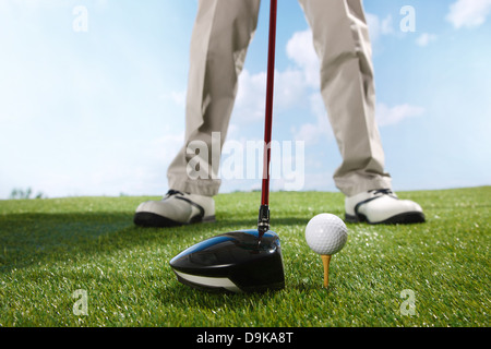 Golf player teeing up to hit ball Stock Photo