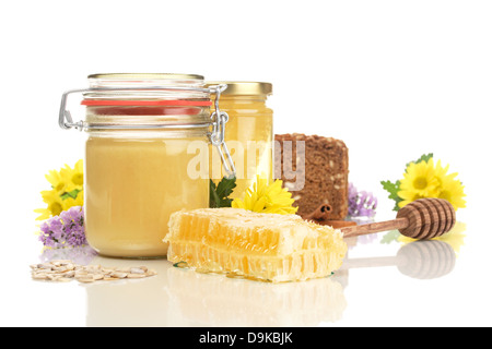 Honey glasses with honeycomb, wholemeal bread, honey spoon, sunflower cores and flowers, Honeycomb jars with honey, wholemeal br Stock Photo