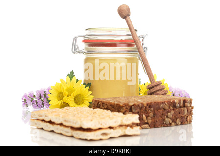 Honey glass with wholemeal bread, crispbread and honey spoon, Honey jar with wholemeal bread, crisp bread and honey spoon Stock Photo