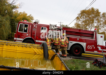 Firefighters at a scene in charge of the tanker water for the pumper engine Stock Photo