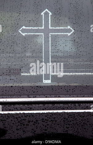 part of hearse window covered in raindrops with cross Stock Photo