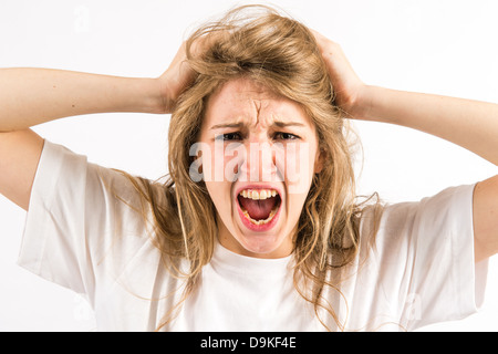 An angry furious shouting yelling young woman tearing at her long blonde hair Stock Photo
