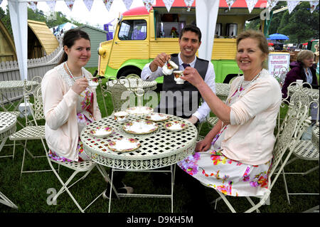 Woodstock, Oxfordshire, UK. 21st June 2013. Woodstock, Oxfordshire, UK. 21st June 2013. Patricia and Claudia Cook with Daniel Elsey on their vintage themed cream tea stall at the Blenheim Palace Flower Show, Woodstock, Oxfordshire UK 21st June 2013.  Today was opening day of the show which runs from 21st to 23rd June.  The show attracted thousands of visitors on the opening day who came to see stunning floral displays, gardening products, food and drink stands and celebrity speakers. Credit:  Julian Eales/Alamy Live News Stock Photo