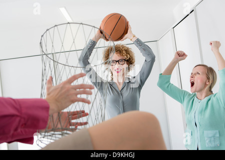 Office workers playing basketball with litter bin