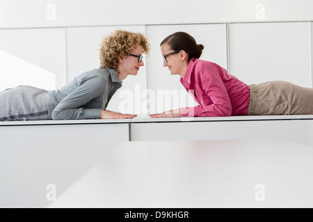 Two women lying on desk face to face