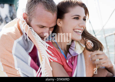 Young couple on yacht wrapped in blanket Stock Photo