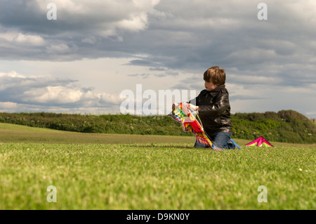 Boy assembles kite in grass field Stock Photo