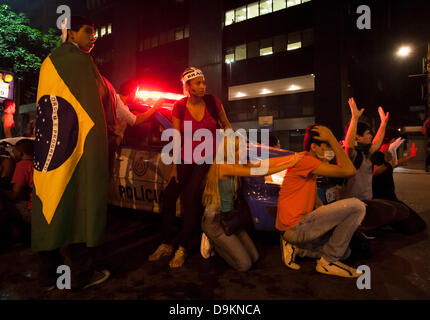 Rio de Janeiro, Brazil  20th June 2013. Frightened protesters shelter around a military police car in Avenida Rio Branco, as the ´Batalhão de Choque´, Riot Control Police´ pass by close by, after dispersing protesters using tear gas and rubber bullets in the centre of Rio de Janeiro, Brazil  20th June 2013 Credit:  Peter M. Wilson/Alamy Live News Stock Photo