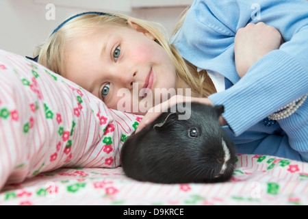 Portrait of young girl stroking pet guinea pig Stock Photo