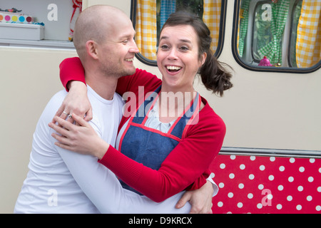 Mid adult couple embracing outside of caravan Stock Photo