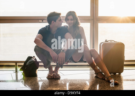 Young couple sitting on railing in airport Stock Photo