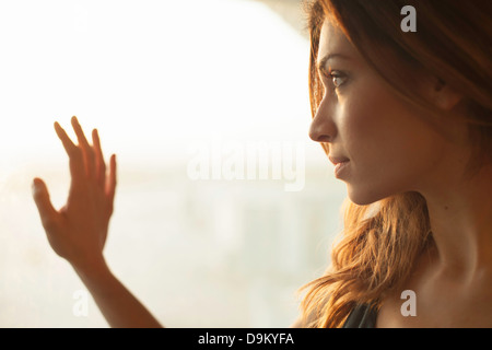 Young woman looking out of window Stock Photo