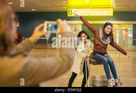 Woman photographing two teenage girls in airport Stock Photo