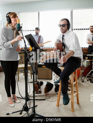 Young caucasian musicians, band performing on blue studio background in