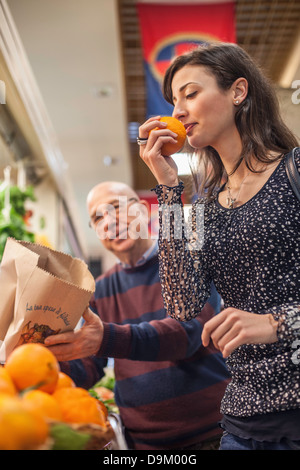 Woman smelling fresh oranges in market Stock Photo