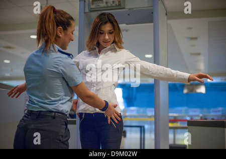 Security guard checking female passenger in airport security Stock Photo