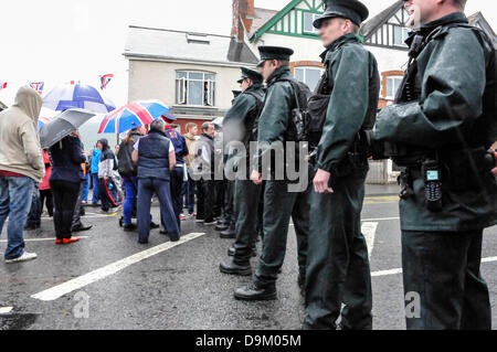 Uniformed PSNI police officers wearing high visibility jackets form a line across a road to stop a crowd from proceeding Stock Photo