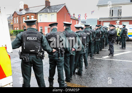 Uniformed PSNI police officers wearing high visibility jackets form a line across a road to stop a crowd from proceeding Stock Photo