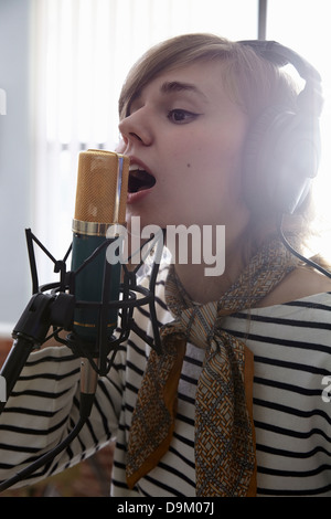 Young woman singing into microphone Stock Photo