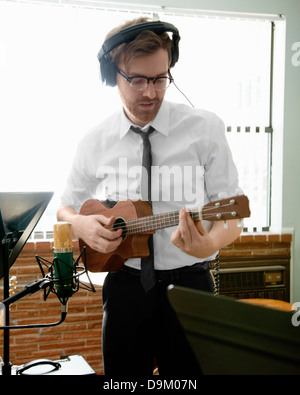 Young man playing ukulele in music room rehearsal Stock Photo