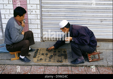 Chinese men playing Xiangqi also called Chinese chess which is a strategy board game in a sidewalk in the town of Tongren in Guizhou province China Stock Photo