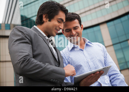 Two businessmen looking at a digital tablet and smiling Stock Photo