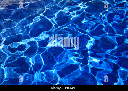 Abstract Patterns Created By Sunlight Dancing On The Undulating Surface Of Deep Blue Swimming Pool Water Stock Photo